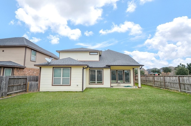 rear view of property with a lawn, roof with shingles, and a fenced backyard