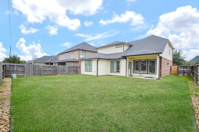 back of property featuring a yard, roof with shingles, and a fenced backyard