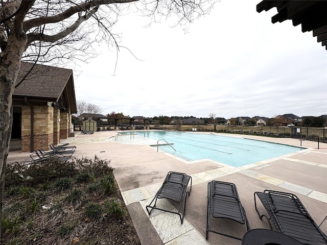 community pool with a patio area and fence