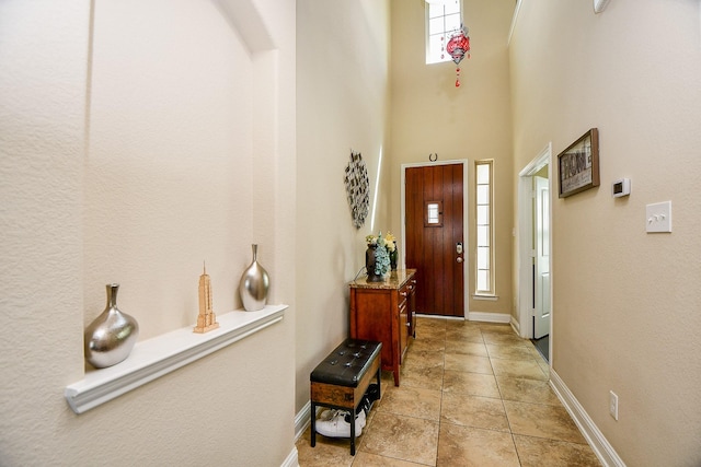 foyer entrance with a high ceiling, baseboards, a wealth of natural light, and light tile patterned floors