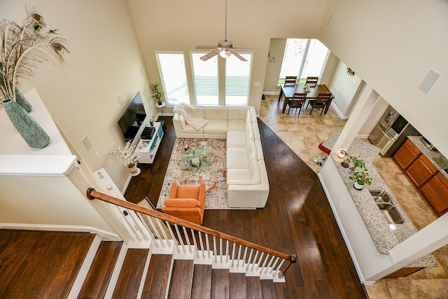 living room featuring wood finished floors, a high ceiling, a ceiling fan, and a wealth of natural light