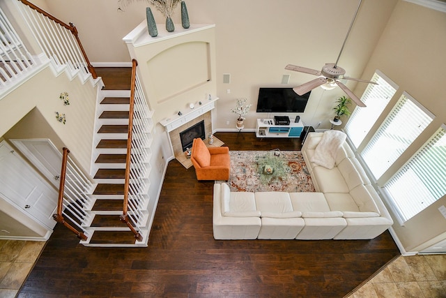 living room with a towering ceiling, stairs, ceiling fan, and a healthy amount of sunlight