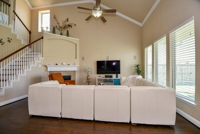 living area featuring high vaulted ceiling, stairs, ceiling fan, a fireplace, and dark wood-style flooring