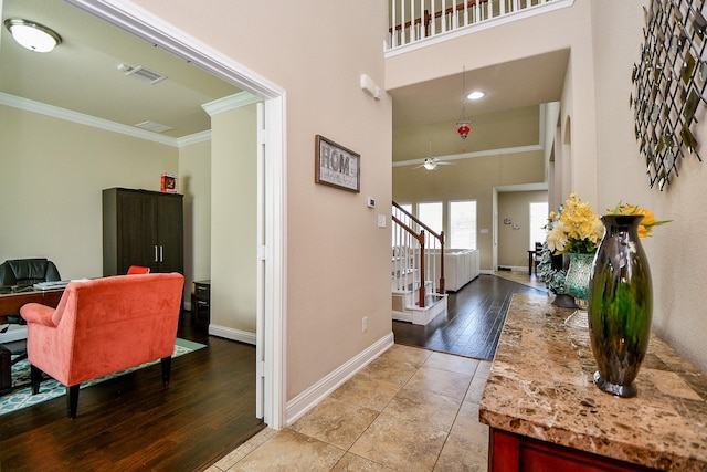 entrance foyer featuring a towering ceiling, ornamental molding, baseboards, stairs, and ceiling fan