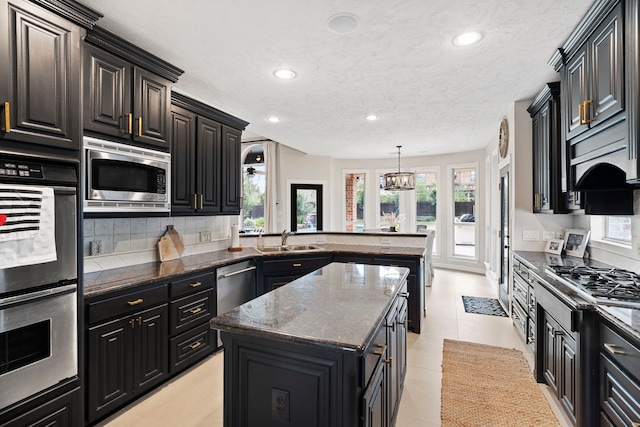 kitchen with decorative light fixtures, sink, dark stone countertops, a kitchen island, and stainless steel appliances