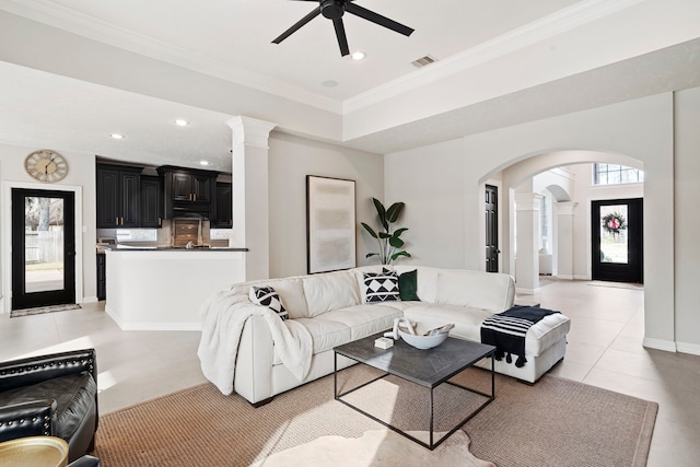 tiled living room with ceiling fan, ornate columns, and crown molding