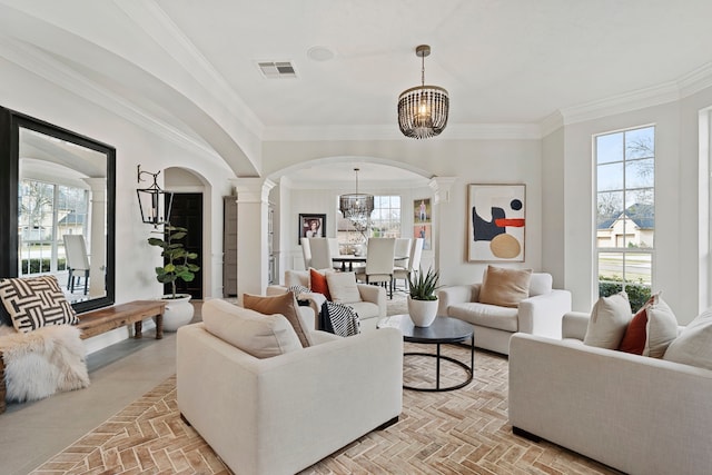 living room with ornate columns, a healthy amount of sunlight, and an inviting chandelier