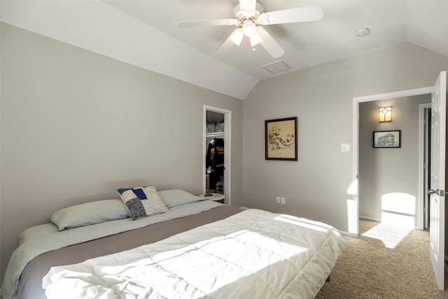 bedroom with ceiling fan, a walk in closet, lofted ceiling, and carpet flooring