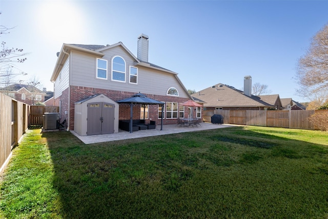 back of property with a lawn, a shed, a gazebo, a patio area, and central air condition unit