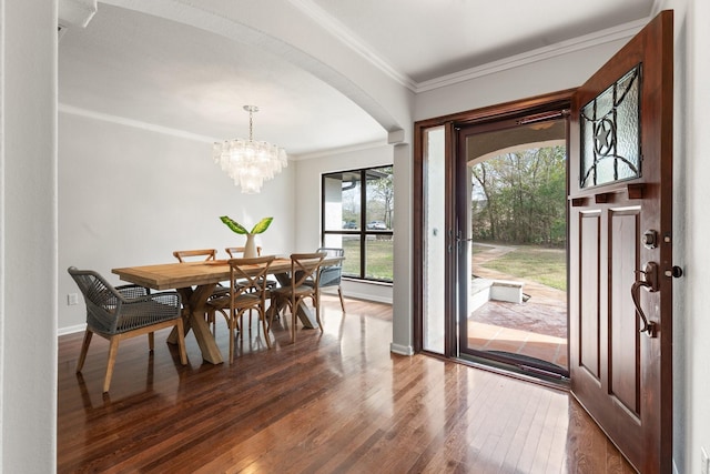 dining space featuring dark hardwood / wood-style flooring, crown molding, and a notable chandelier