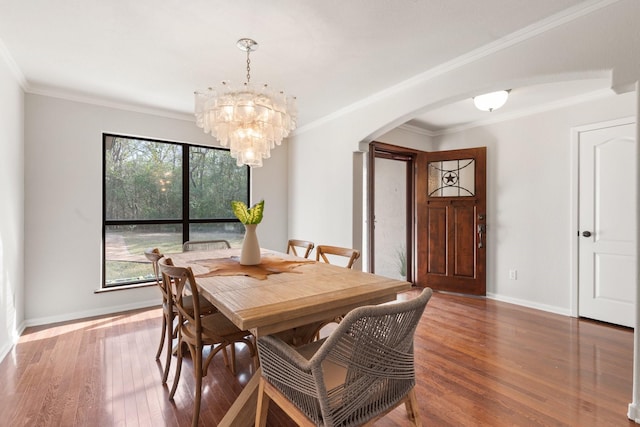 dining area featuring arched walkways, crown molding, wood finished floors, and baseboards