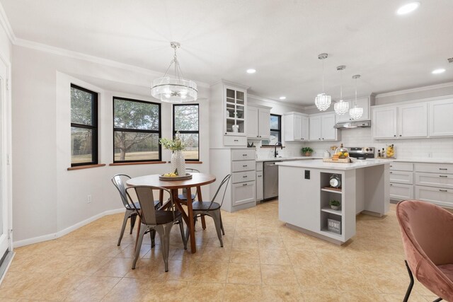 kitchen featuring a kitchen island, decorative backsplash, crown molding, hanging light fixtures, and stainless steel appliances