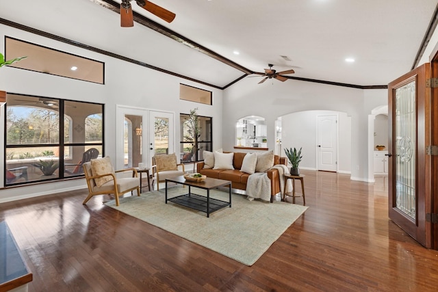 living area with arched walkways, a ceiling fan, baseboards, ornamental molding, and dark wood-style floors