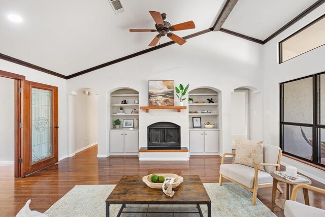 living room with ceiling fan, built in shelves, dark hardwood / wood-style floors, and lofted ceiling with beams