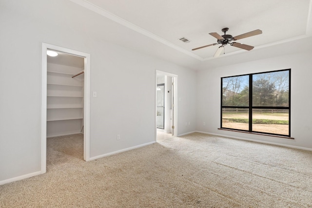 unfurnished bedroom with carpet flooring, visible vents, baseboards, a spacious closet, and a tray ceiling