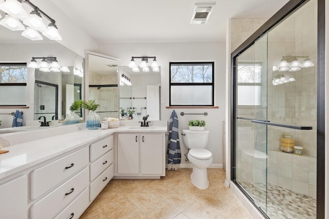 full bathroom with double vanity, visible vents, toilet, a stall shower, and a sink