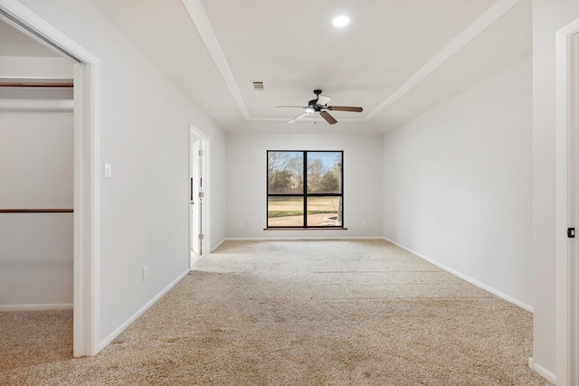 carpeted spare room with visible vents, a raised ceiling, a ceiling fan, and baseboards