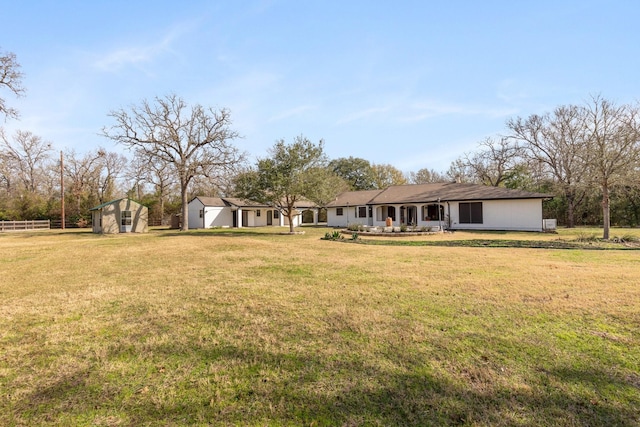 exterior space featuring a storage unit, fence, a lawn, and an outdoor structure