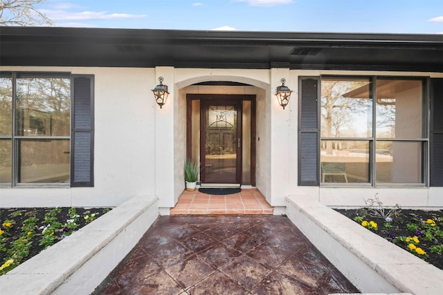 doorway to property with covered porch and stucco siding