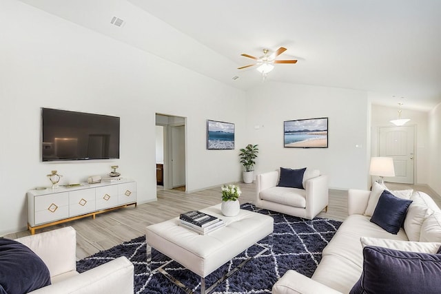 living room with ceiling fan, hardwood / wood-style floors, and vaulted ceiling