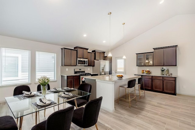 kitchen with appliances with stainless steel finishes, dark brown cabinets, hanging light fixtures, and a center island