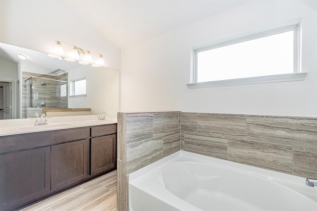 bathroom with shower with separate bathtub, vanity, and vaulted ceiling