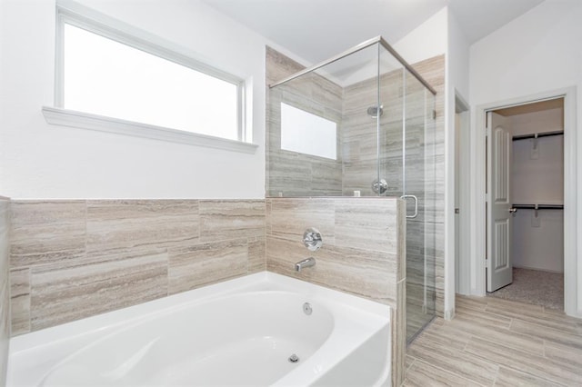 bathroom featuring a wealth of natural light and shower with separate bathtub