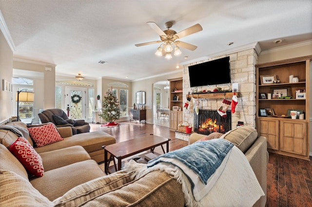 living room featuring ceiling fan, dark hardwood / wood-style flooring, crown molding, and a fireplace