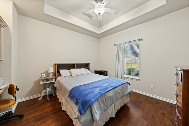 bedroom featuring dark wood-type flooring, ceiling fan, and a tray ceiling