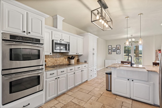 kitchen with light stone counters, white cabinets, pendant lighting, and appliances with stainless steel finishes