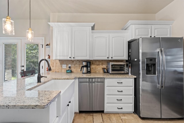 kitchen with white cabinets, appliances with stainless steel finishes, decorative backsplash, hanging light fixtures, and light stone counters