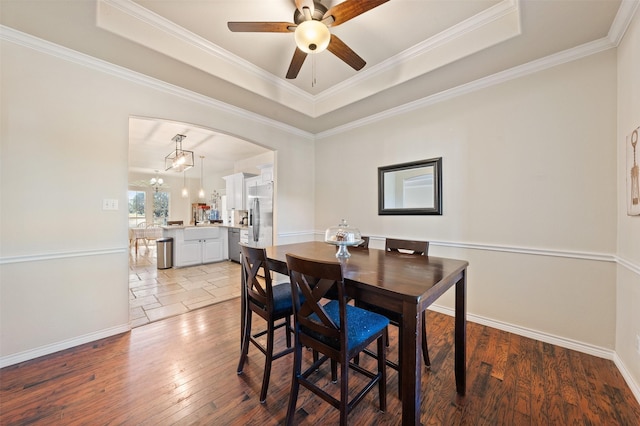 dining space featuring ceiling fan with notable chandelier, a tray ceiling, and ornamental molding