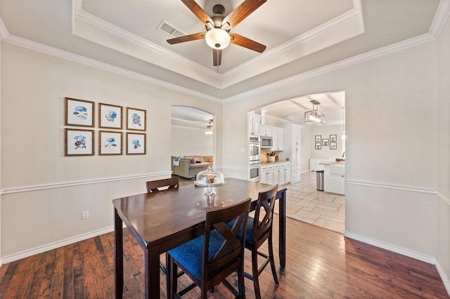 dining space featuring a raised ceiling, ceiling fan, and crown molding