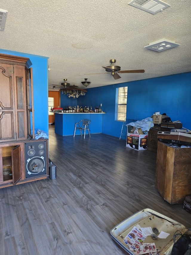 interior space with ceiling fan, a textured ceiling, dark hardwood / wood-style floors, and bar area