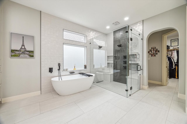 bathroom featuring independent shower and bath, tile patterned flooring, and tile walls