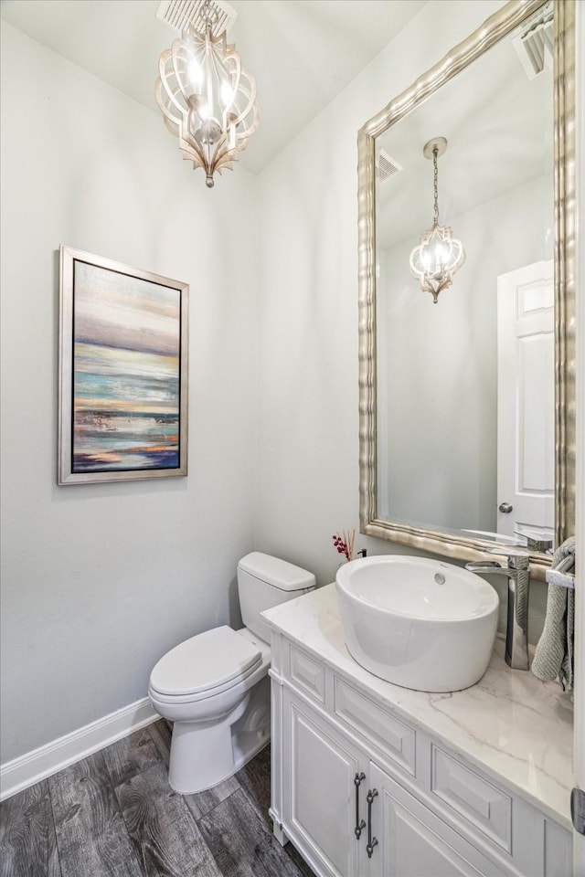 bathroom featuring hardwood / wood-style flooring, vanity, a notable chandelier, and toilet