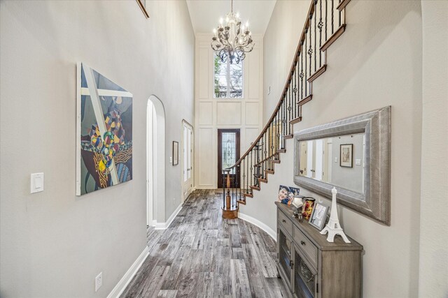 foyer entrance with wood-type flooring, a chandelier, and a high ceiling