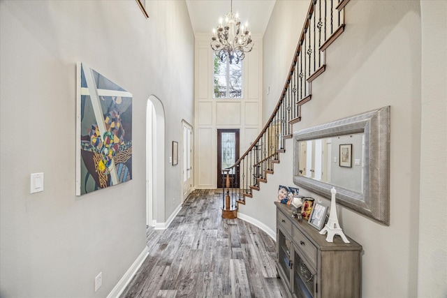 entrance foyer featuring wood-type flooring, a chandelier, and a high ceiling