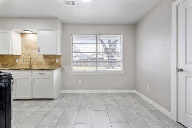 kitchen with white cabinetry, decorative backsplash, stone countertops, a textured ceiling, and sink