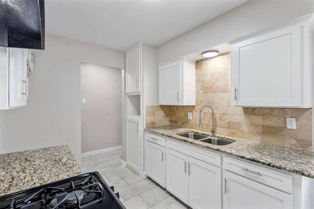 kitchen featuring light stone countertops, sink, and white cabinetry