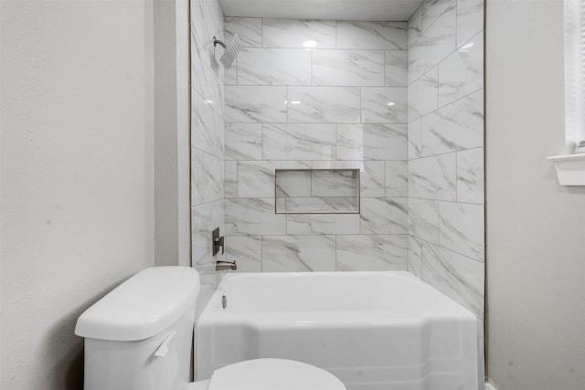 bathroom featuring toilet and tiled shower / bath