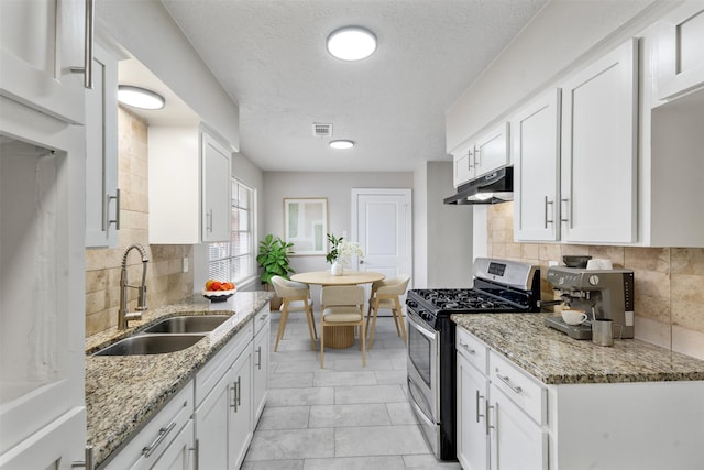 kitchen featuring white cabinetry, decorative backsplash, gas range, light stone countertops, and sink