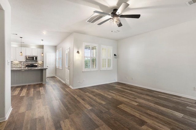 unfurnished living room featuring dark wood-type flooring, sink, and ceiling fan