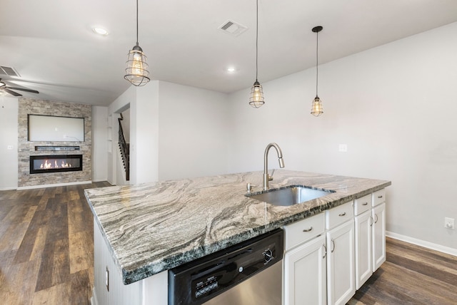 kitchen with pendant lighting, white cabinets, dishwasher, sink, and a center island with sink