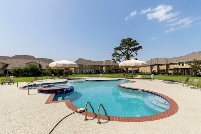 view of swimming pool featuring a community hot tub, a lawn, and a patio