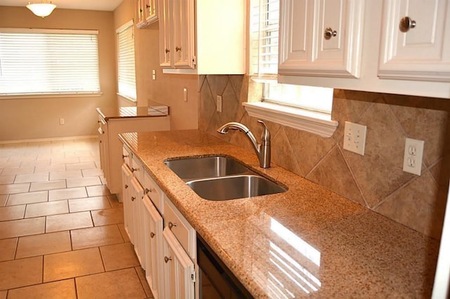 kitchen featuring light tile patterned floors, tasteful backsplash, white cabinets, light stone counters, and sink