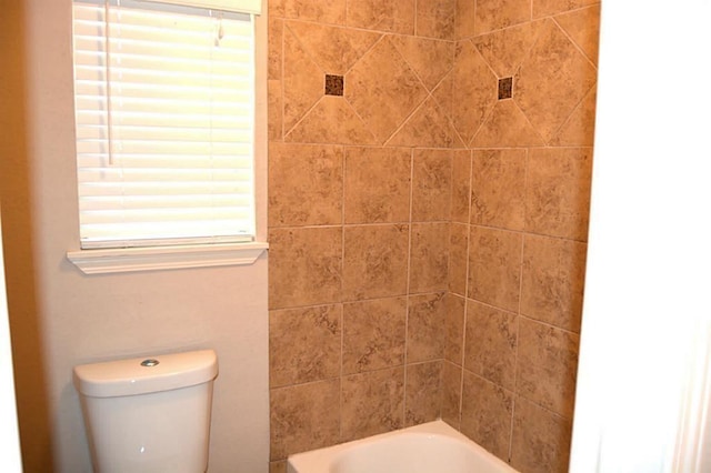 bathroom with toilet and tiled shower / bath combo