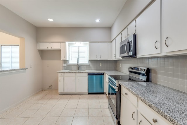 kitchen with light tile patterned floors, tasteful backsplash, appliances with stainless steel finishes, white cabinets, and a sink