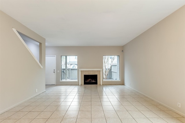 unfurnished living room with light tile patterned flooring, a fireplace, and baseboards