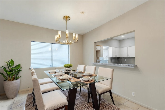 dining area featuring a chandelier, light tile patterned floors, and baseboards